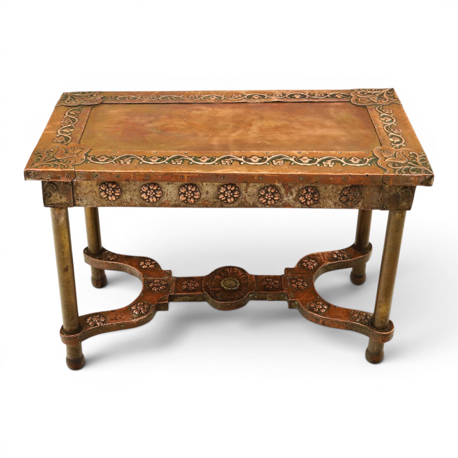 Arts and Crafts copper mounted coffee table, rectangular top with embossed foliate border and stylised corner motifs, studwork detail, on cylindrical supports united by pierced shaped stretcher with applied flowerhead bosses