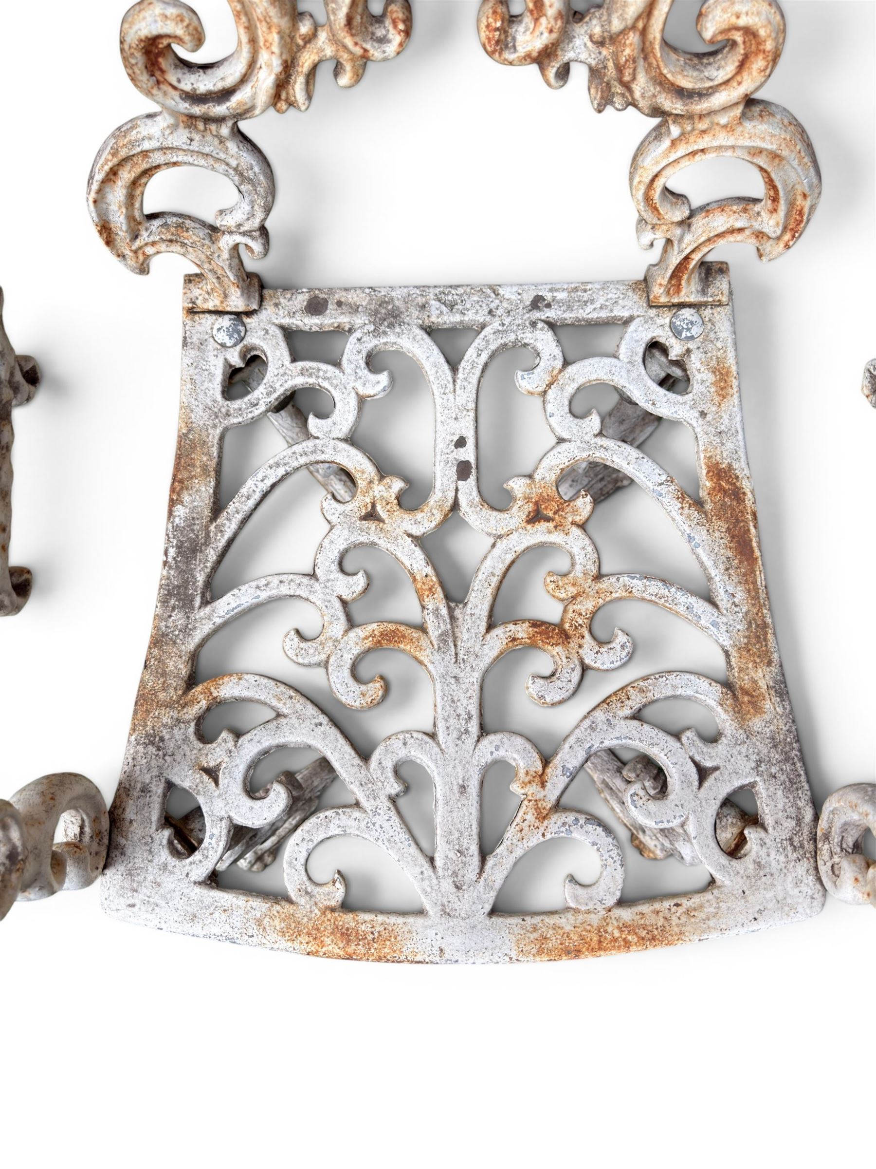 Pair of Victorian cast iron garden chairs, the ornate pierced back of scrolling foliate design, scrolling arm terminals over splayed supports formed of C and S-scrolls, in distressed white painted finish