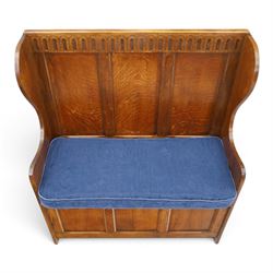 Early 20th century oak box settle, panelled back with arcaded carved rail, swept sides and arms, hinged seat with storage, panelled front