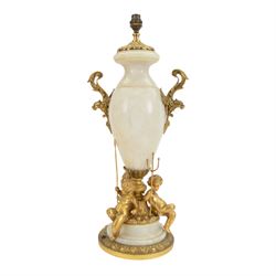 Onyx table lamp, of urn form with scrolling gilt handles, the stepped circular base adorned with three seated putti, H60cm