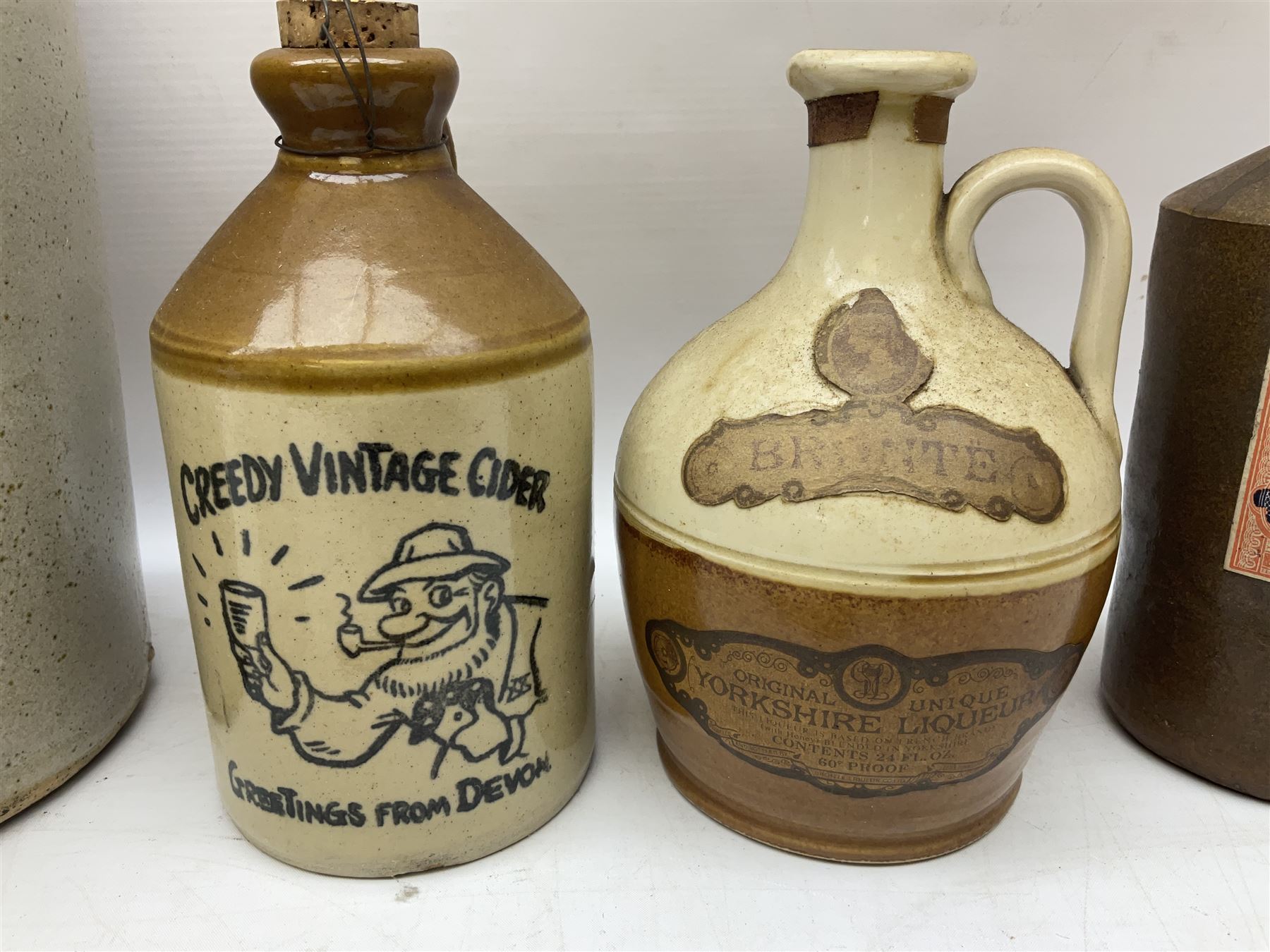Large stoneware two tone flagon with black lettering Folkard Chemist Pavement York, together with two stoneware jugs, Bronte Yorkshire Liqueur and Creedy Vintage Cider, and salt glaze example, together with four vintage glass bottles, tallest H33cm