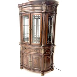 Kevin Charles American walnut demi lune display cabinet with illuminated interior, projecting cornice, two bevel edge glazed doors enclosing two adjustable shelves above single drawer and four cupboard doors with wine rack, carved scrolling supports 