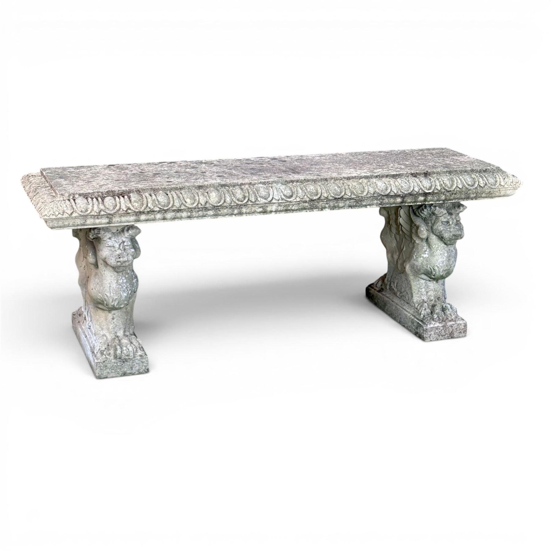 Ornate weathered cast stone rectangular garden bench, raised on winged griffin supports, square plinth bases
