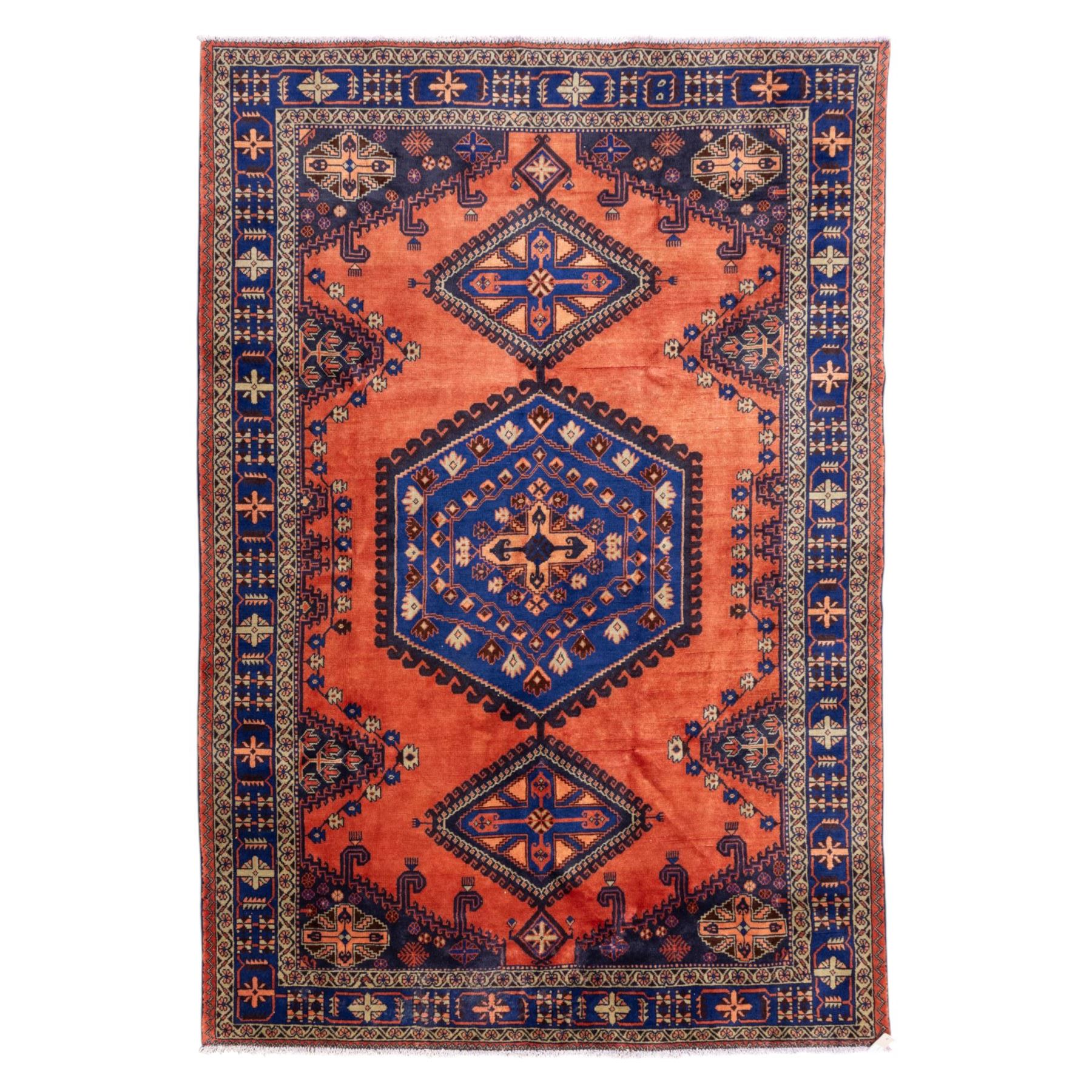 Central Persian Veis hand-knotted carpet, madder red field, decorated with a repeating arrangement of large octagonal and diamond medallions filled with stylized cross and geometric motifs and angular tribal devices within a series of geometric borders in tones of madder red, indigo blue, ivory, and soft green, with cotton fringe ends 
