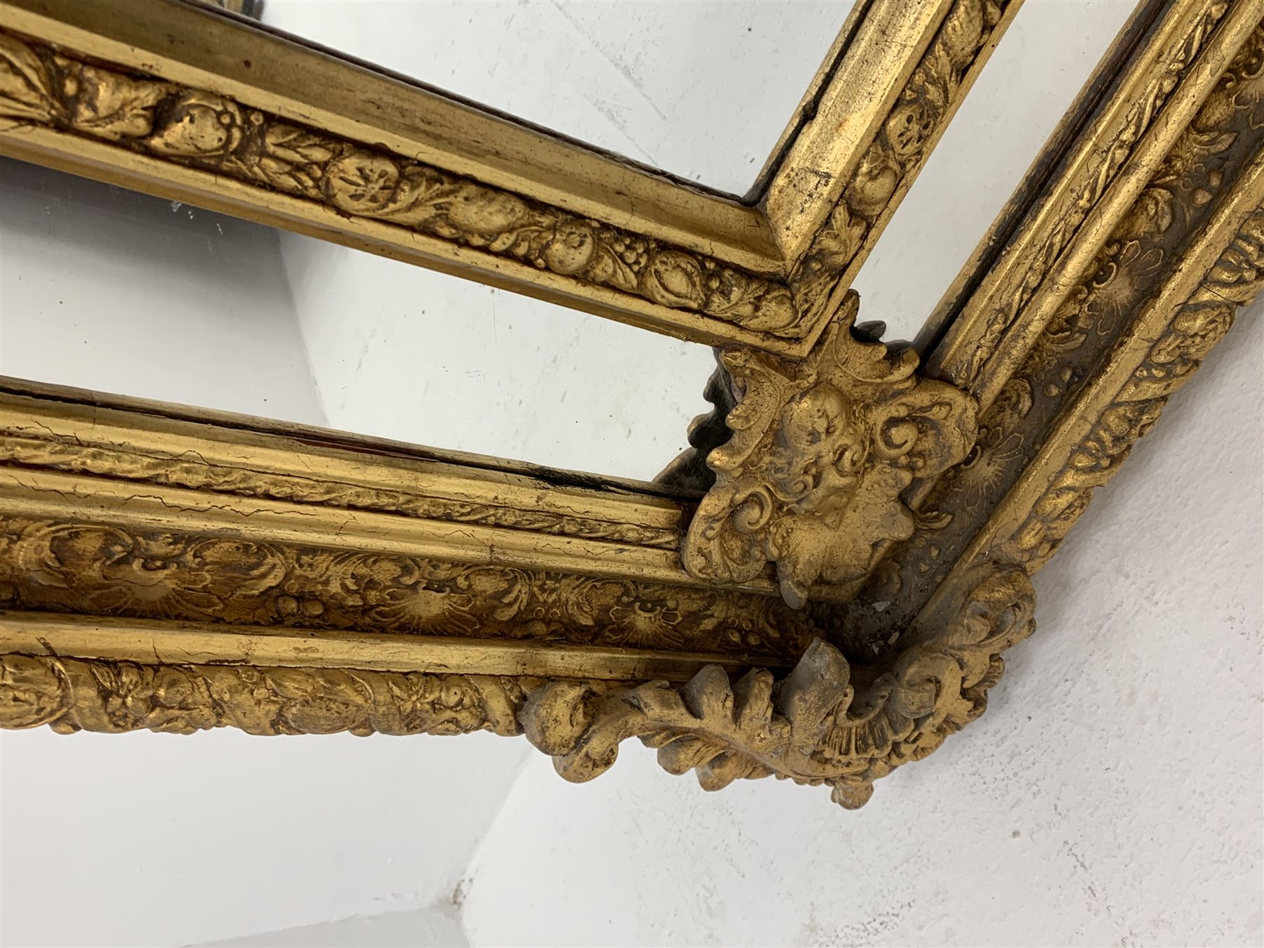 Gilt Rococo style mirror, arched top with central cartouche and oak leaf moulded pediment, floral and fruit moulded surround with segmented glass panels, bevelled central pane, c-scroll shell and acanthus leaf brackets