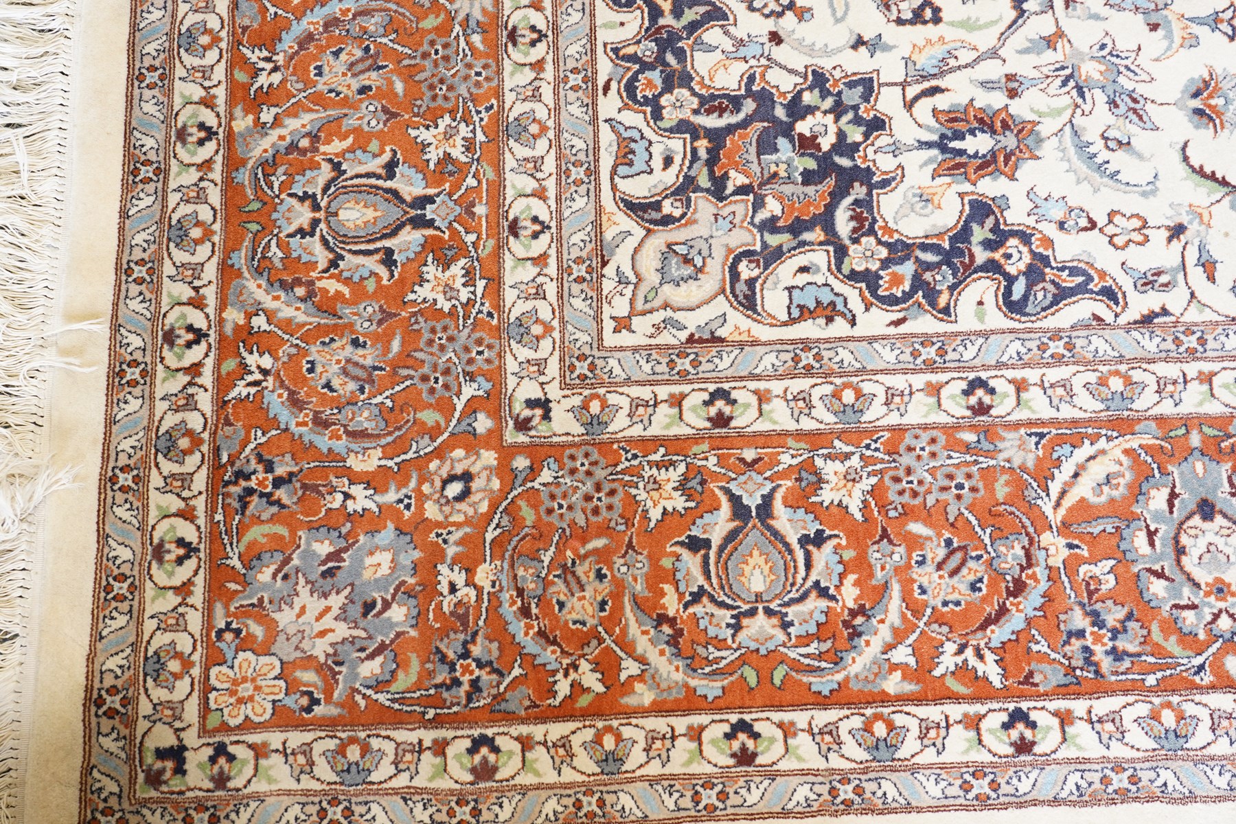 Persian ivory ground Kashan carpet, the busy field decorated with a central floral pole medallion with matching spandrels, the field profusely decorated with scrolling foliate motifs, the crimson guard stripe with repeating scrolling palmettes