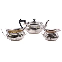 Matched Edwardian silver three piece tea service, comprising teapot with ebonised handle and finial, twin handled sucrier, and milk jug, each of oval part fluted form, with oblique gadrooned rim, hallmarked Jones & Crompton, Birmingham 1907, and Chester 1907, including handle teapot H13.5cm, approximate gross weight 34.75 ozt (1080.9 grams)