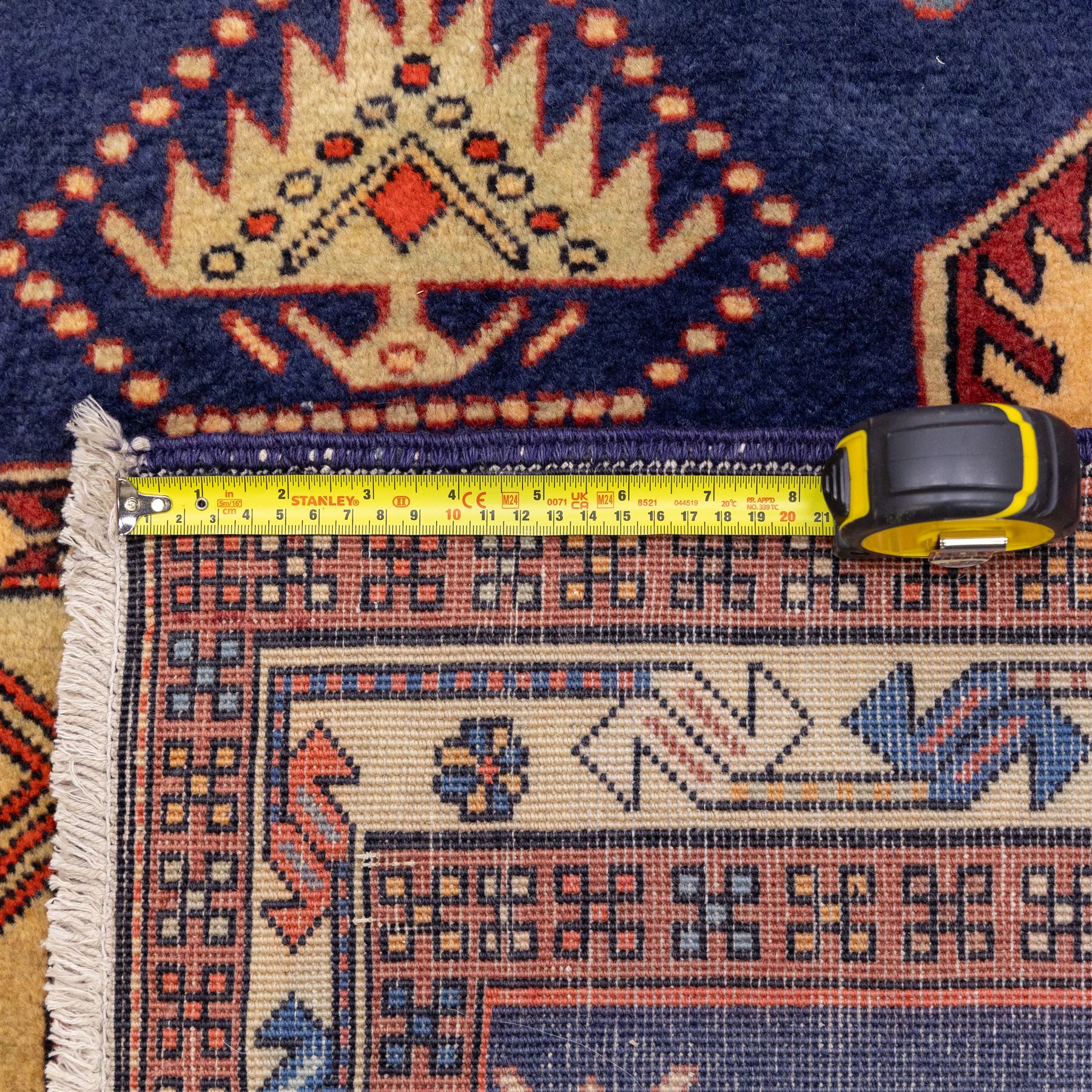 North West Persian Ardebil hand-knotted runner, indigo blue field composed of a repeating series of large stepped octagonal medallions enclosing a central hooked motif and stylized rosette, flanked by angular ivory and madder red latch hook devices, medallions linked by smaller geometric diamonds and serrated lozenges, guard borders with reciprocal motifs and main ivory border decorated with angular vines, with cotton fringe ends 