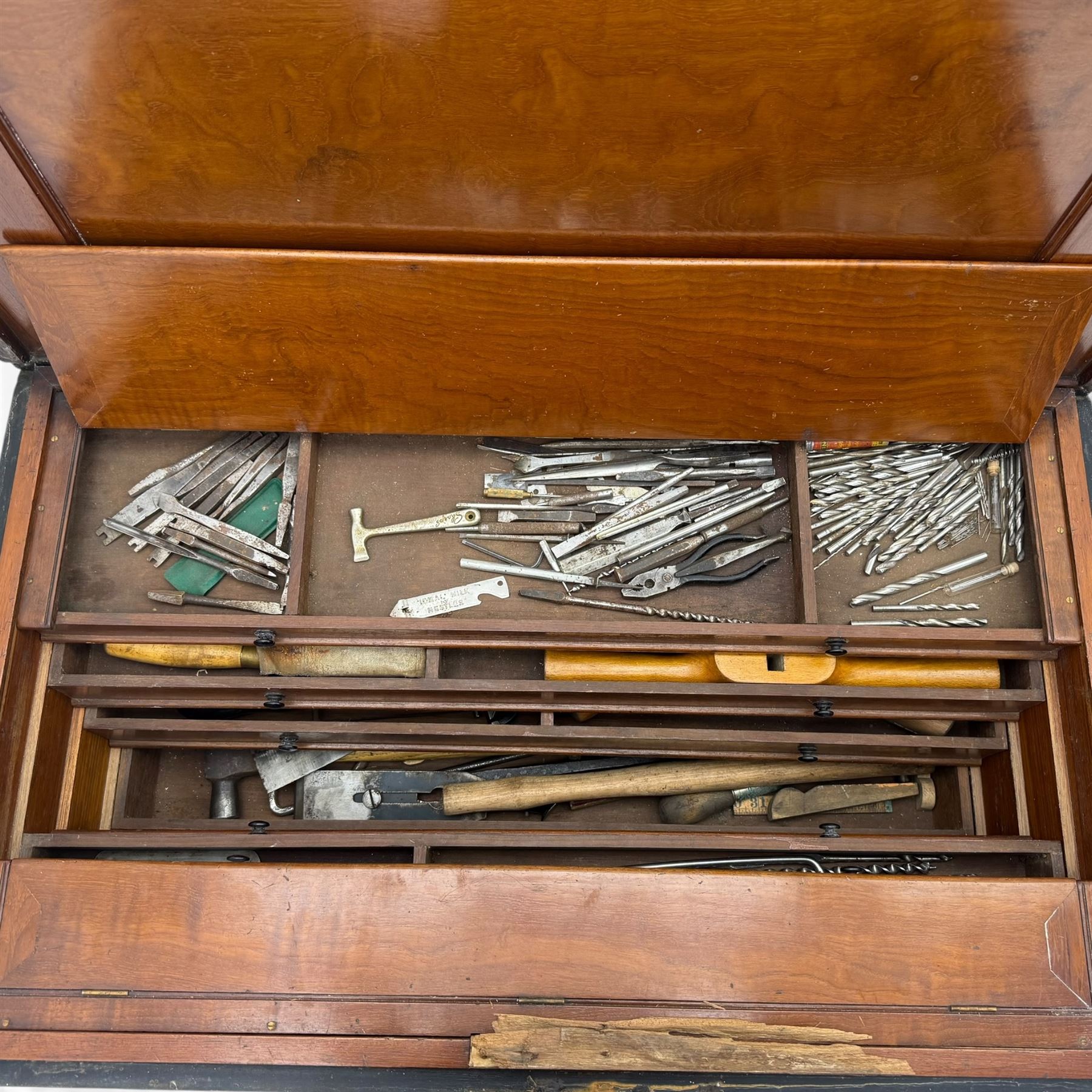 20th century black painted camphorwood lined tool chest, rectangular hinged lid over moulded edge, black painted exterior with iron straps and carry handles, the interior fitted with sliding lidded trays and drawers with turned handles, containing an assortment of hand tools