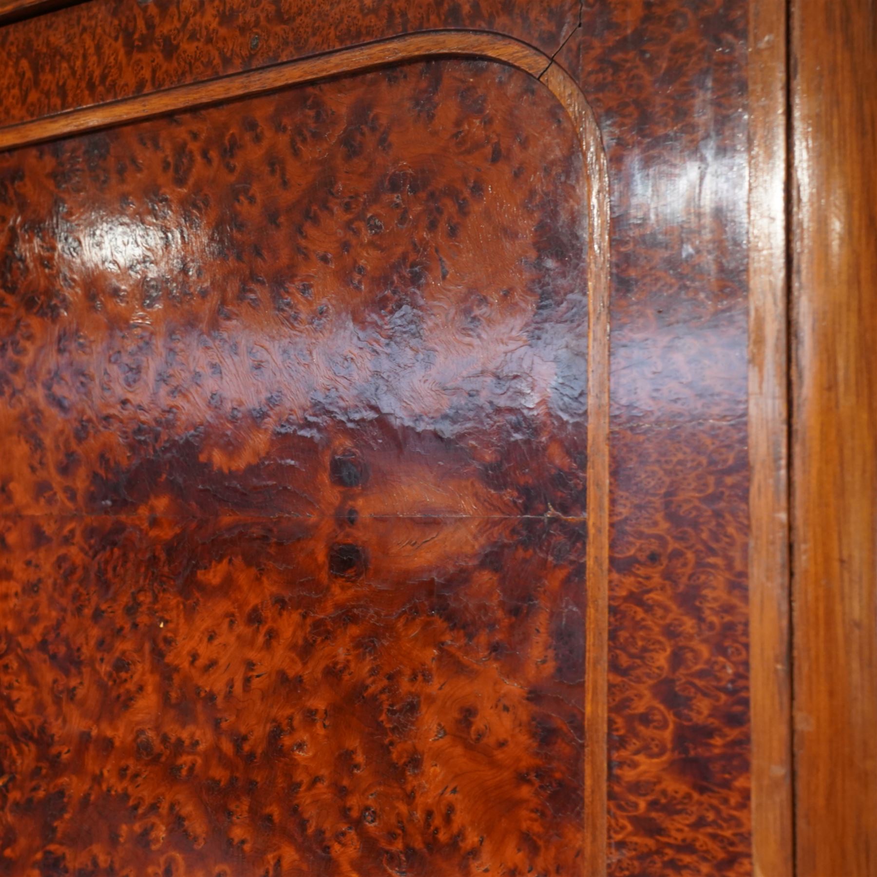 Early 20th century French burr maple breakfront armoire, enclosed by three panelled doors with bookmatched veneer and stringing, outer doors inlaid with gilt urn medallions, fitted interior with hanging spaces flanking a shelved compartment, raised on short tapered legs