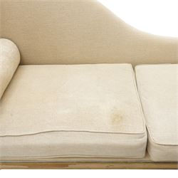 19th century French painted day bed, asymmetrical scrolled ends flanking a serpentine upholstered back, with upholstered end panels, loose seat cushions and cylindrical bolsters upholstered in beige fabric, with turned uprights with fluted detailing, moulded seat rail and lozenge-moulded corner blocks, raised on turned tapering supports
