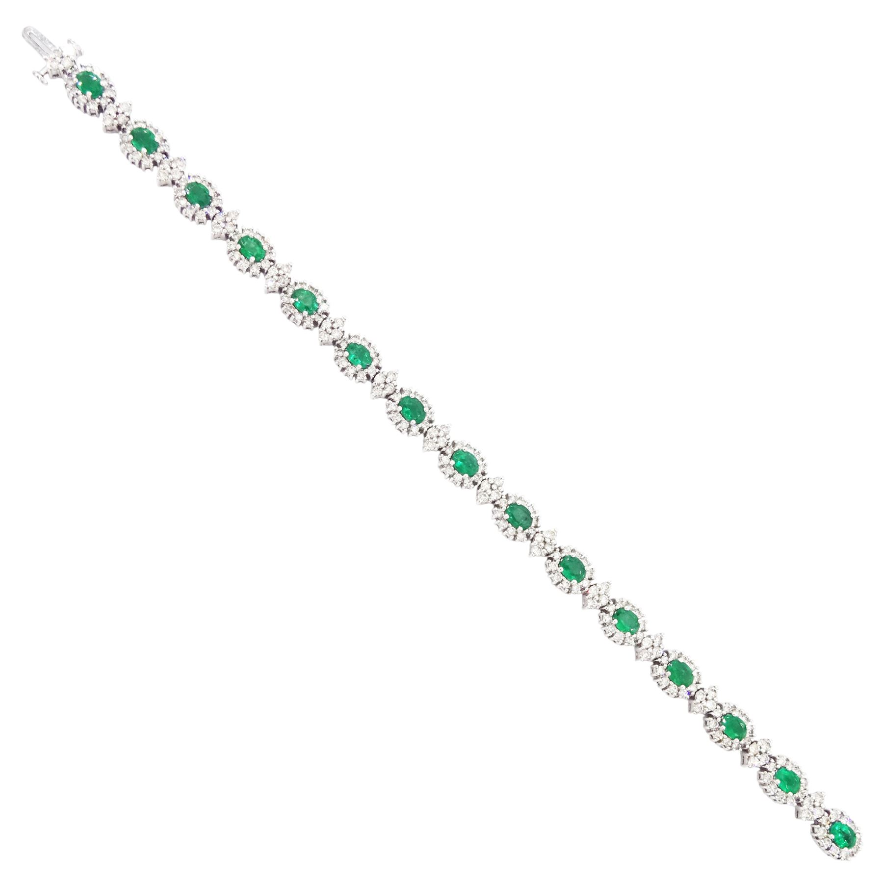 18ct white gold emerald and diamond bracelet, fifteen oval cut emeralds, each surrounded by ten round brilliant cut diamonds and spaced by a further four diamonds, stamped, total emerald weight approx 3.30 carat, total diamond weight approx 2.10 carat