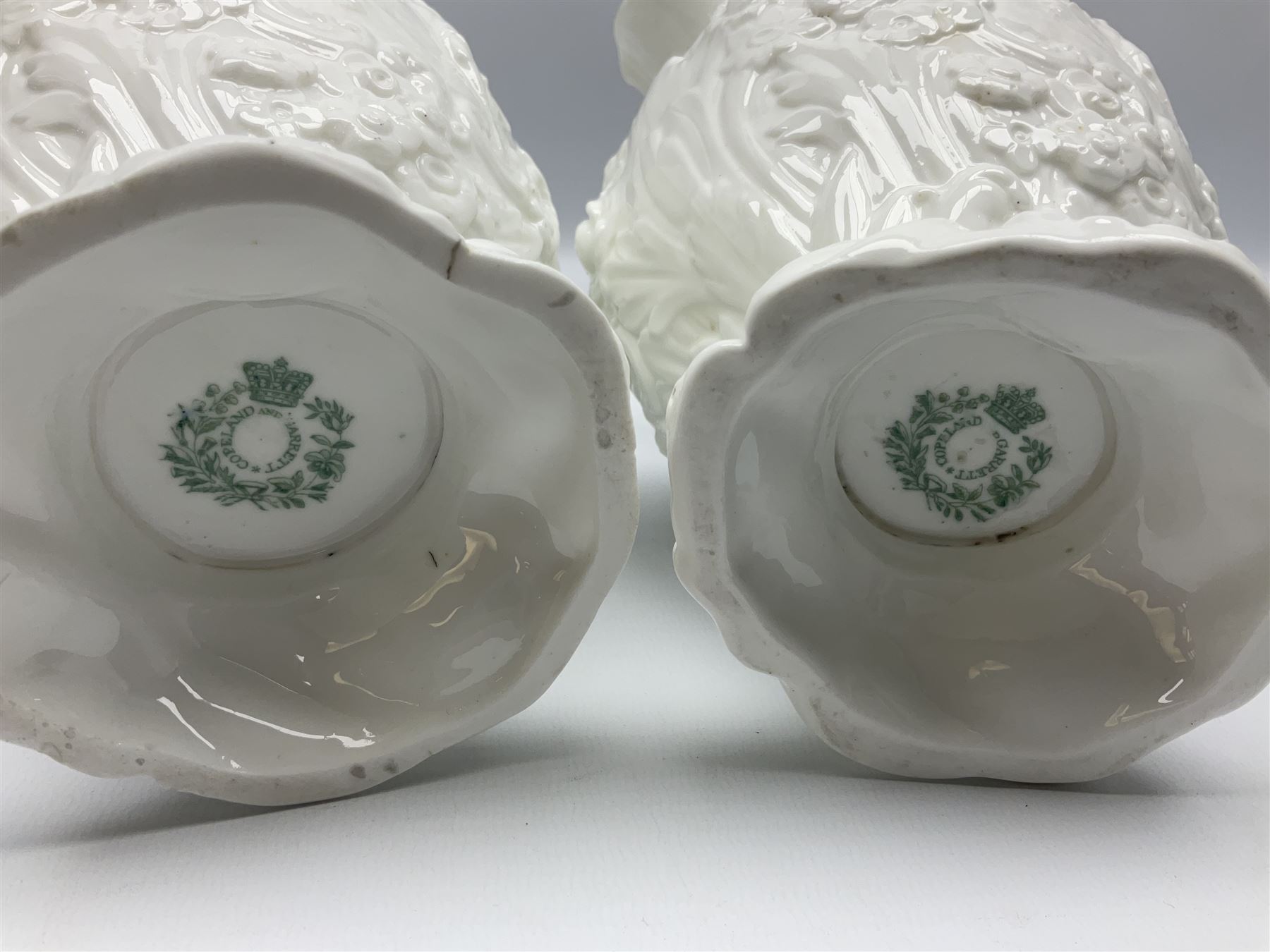 Pair of early/mid 19th century Copeland and Garrett white glazed pitchers, modelled in the Georgian style and moulded with the figures of Venus the Roman Goddess of Love, and Aurora the Roman Goddess of Dawn, within C scroll borders and foliate surround, the naturalistically modelled handle leading to a fruiting vine beneath the rim, upon a spreading base moulded with seashells, with printed green crowned wreath mark beneath, H20cm