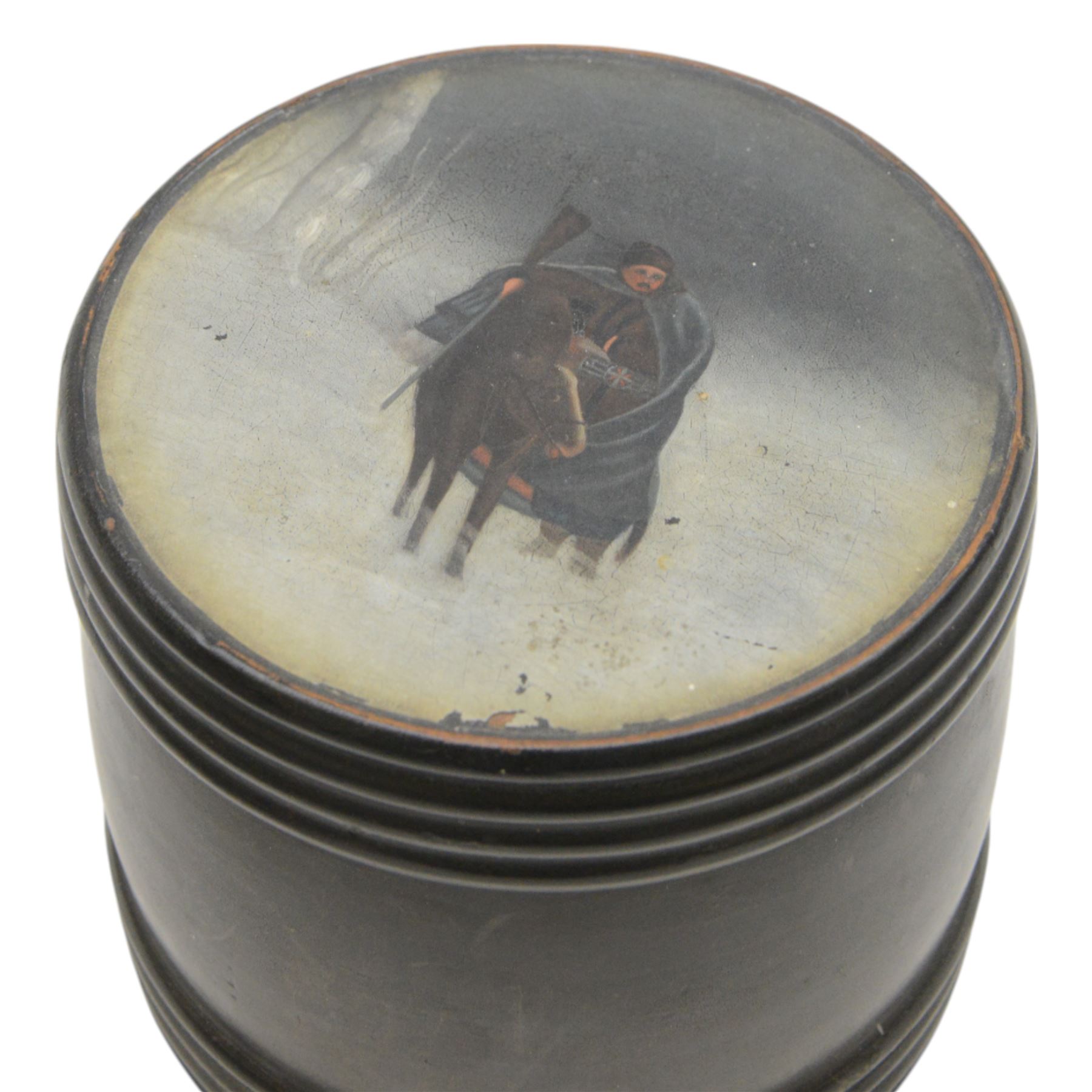 19th Century Russian lacquered tobacco box the painted panel top depicting a man on horseback in the snow, together with two horn pin cushions upon wooden plinths 