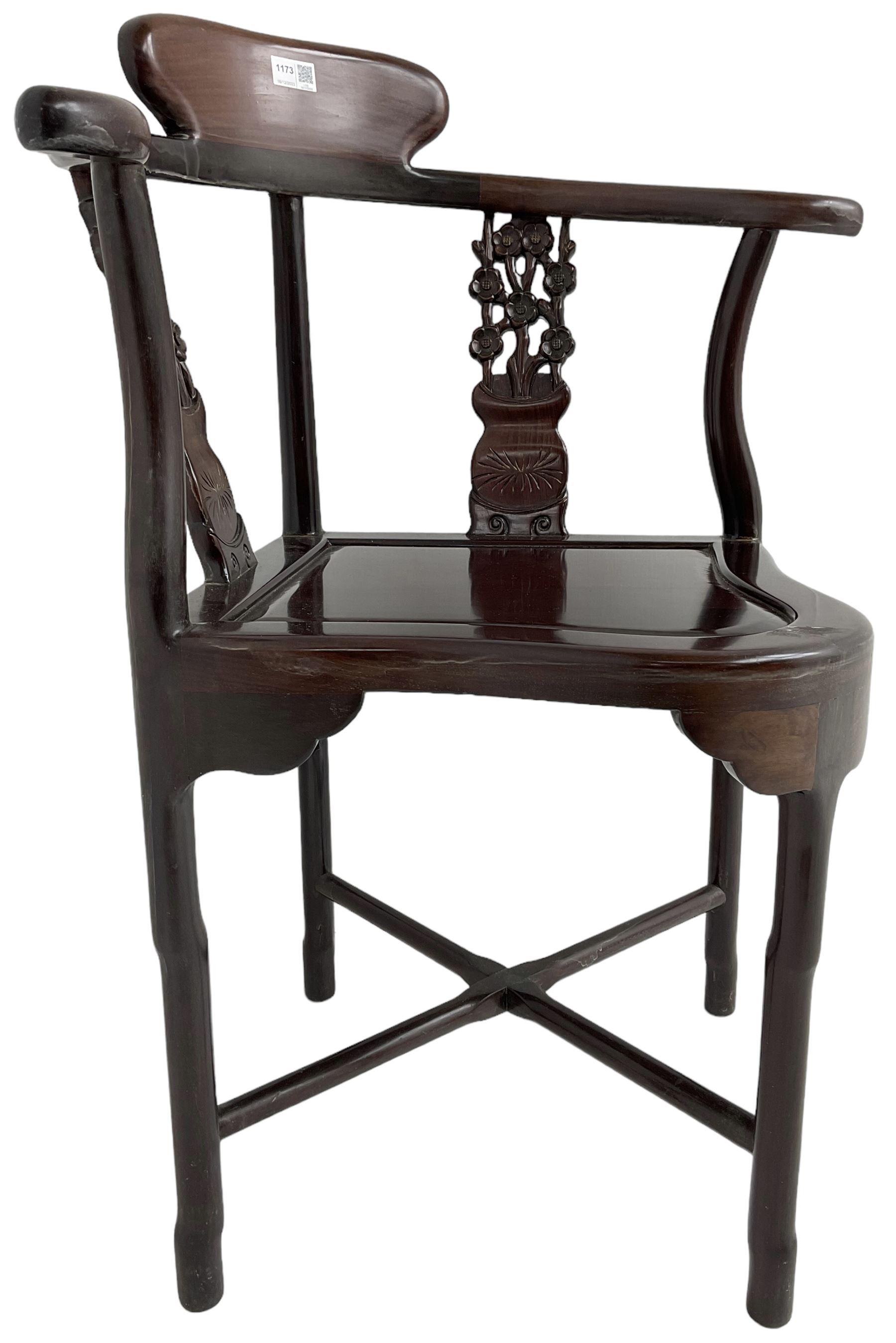 Chinese carved hardwood corner chair, outswept arms over pierced and carved floral splats, raised on shaped cylindrical supports united by X-stretcher