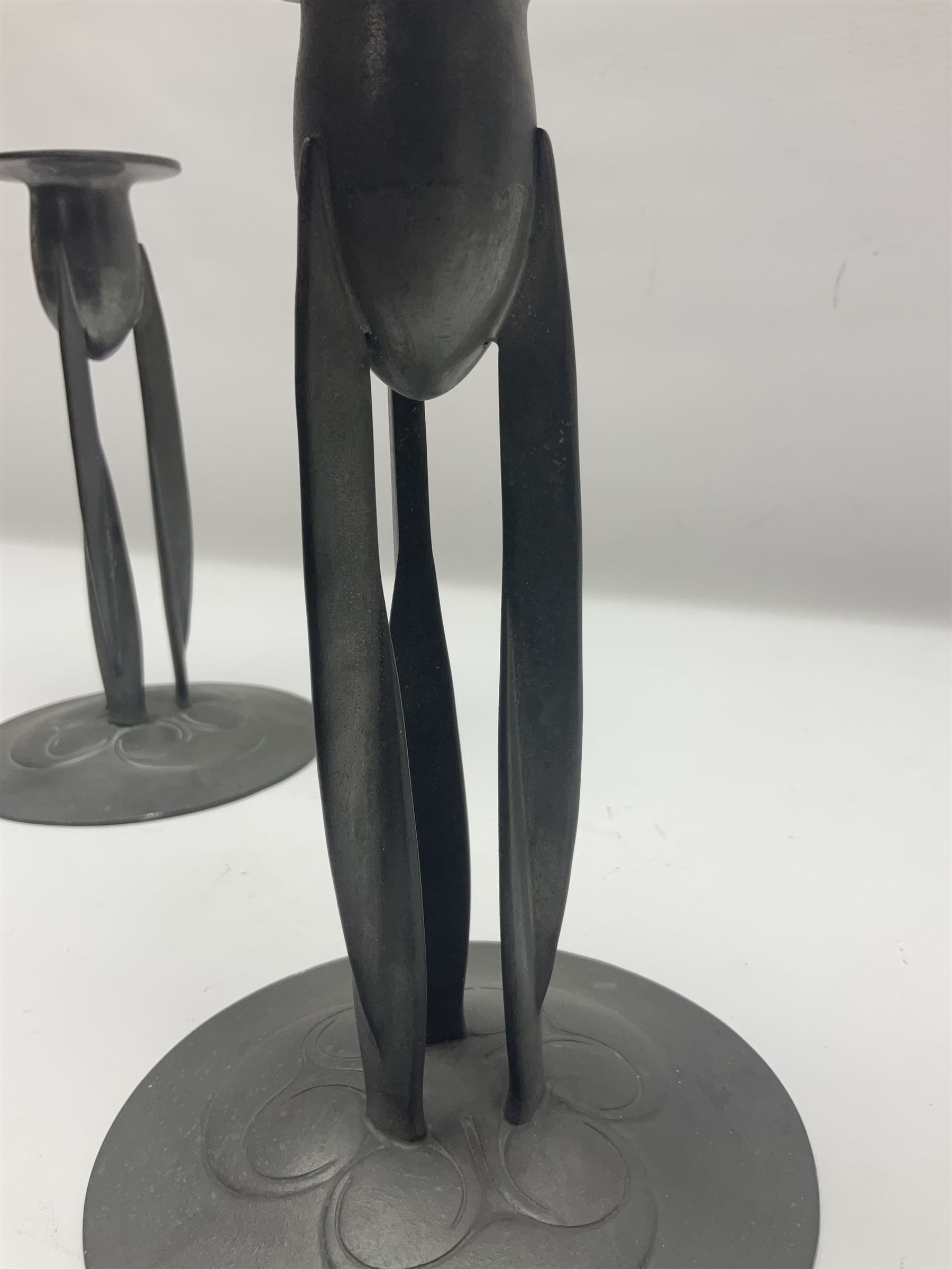 Pair of Solkets English pewter candlesticks, the bud shaped sockets raised upon three angular fin supports and a slightly domed circular base with cast stylised foliate decoration, H23cm