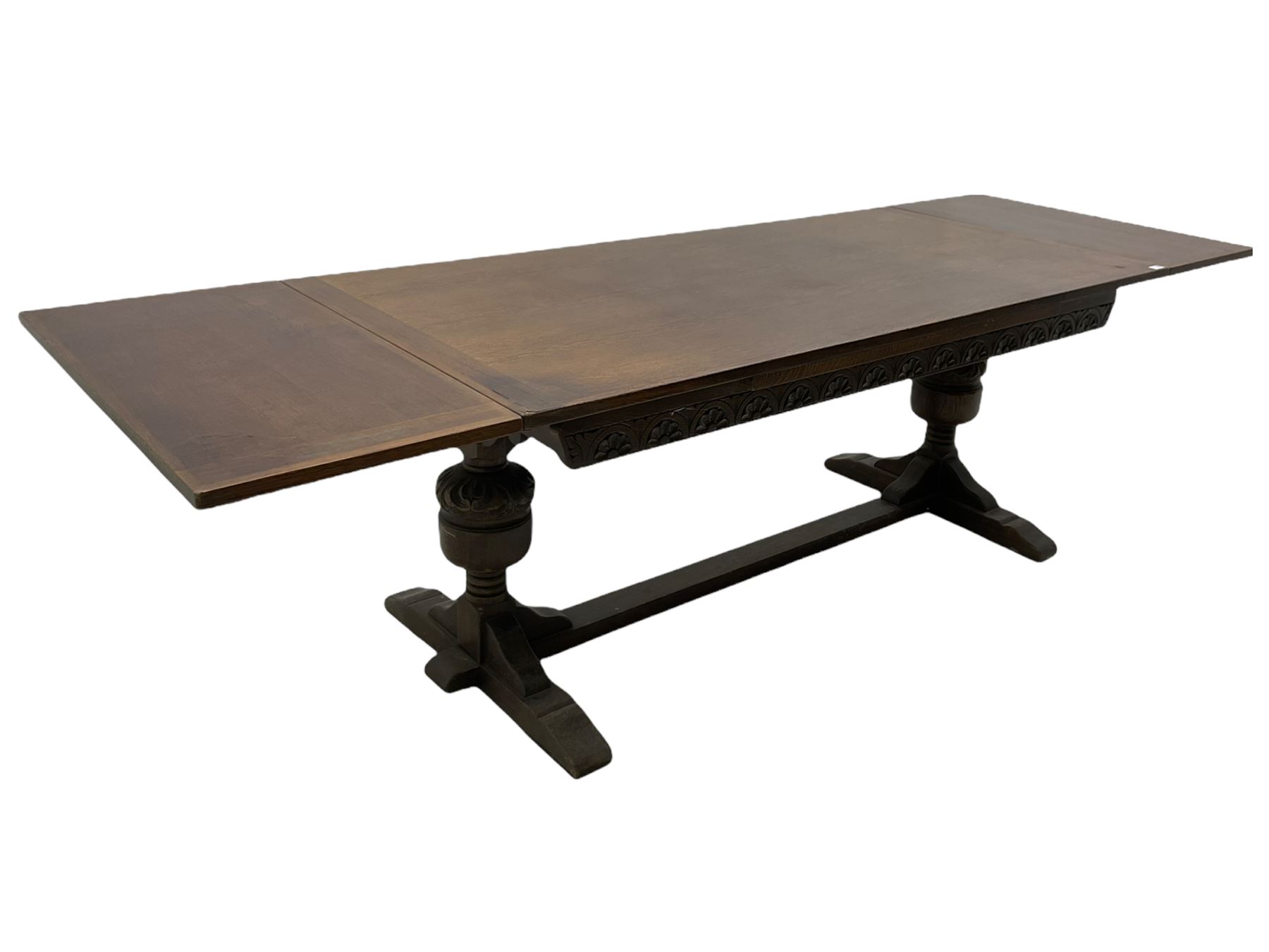 20th century oak drawer leaf extending dining table, two foliage carved baluster supports on sledge feet joined by floor stretcher 
