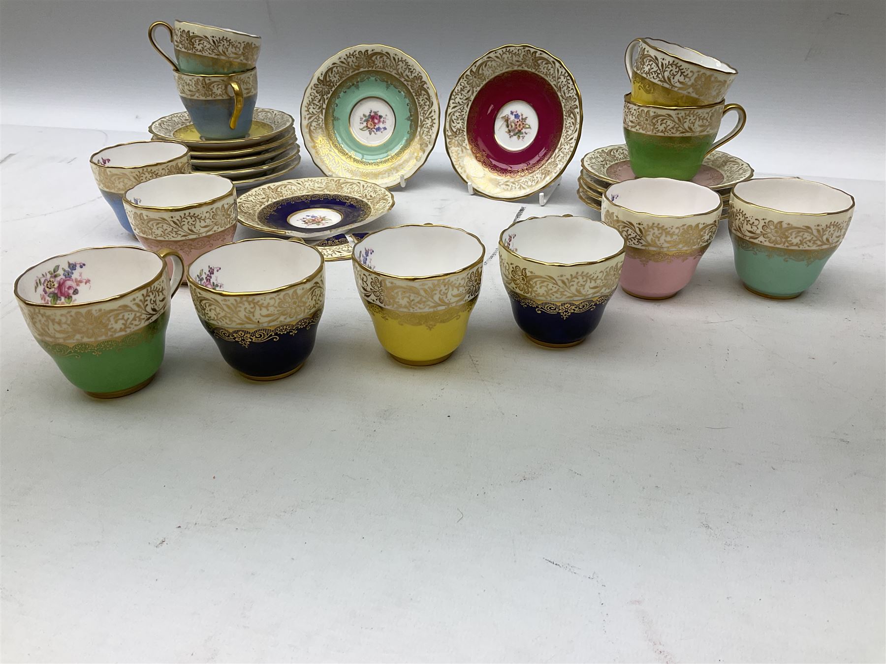 Twelve Spode Ruskin pattern coffee cups and saucers, with floral bouquets, varying colour grounds and gilt
