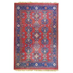 Indian Kayam rug, the rectangular field with repeating geometric medallions on a red ground, within a blue border of stylised floral motifs, with guard borders and fringe terminals