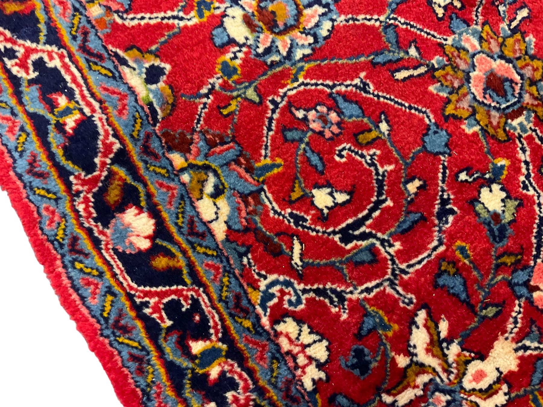 Central Persian Kashan crimson ground runner rug, the field decorated with interlacing branch and stylised flower head motifs, the guarded indigo border with repeating trailing foliate patterns