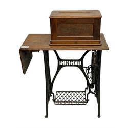 Singer - early 20th century cast iron treadle sewing machine, with hand crank wheel and oak work surface, the machine decorated with gilt foliate detail, complete with rectangular wooden cover and folding extension leaf