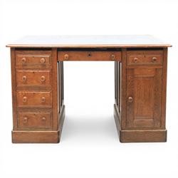 20th century oak compact pedestal desk, tooled green leather inset top, above a single frieze drawer, with a bank of four graduated drawers and a drawer and cupboard, panelled sides raised on castors