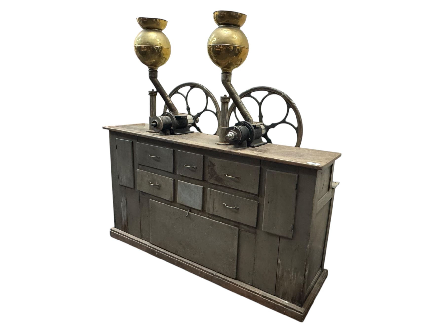 Cabinet with multiple drawers and cupboards mounted with two industrial coffee grinders with large flywheels and brass coffee reservoirs, early 20th century 