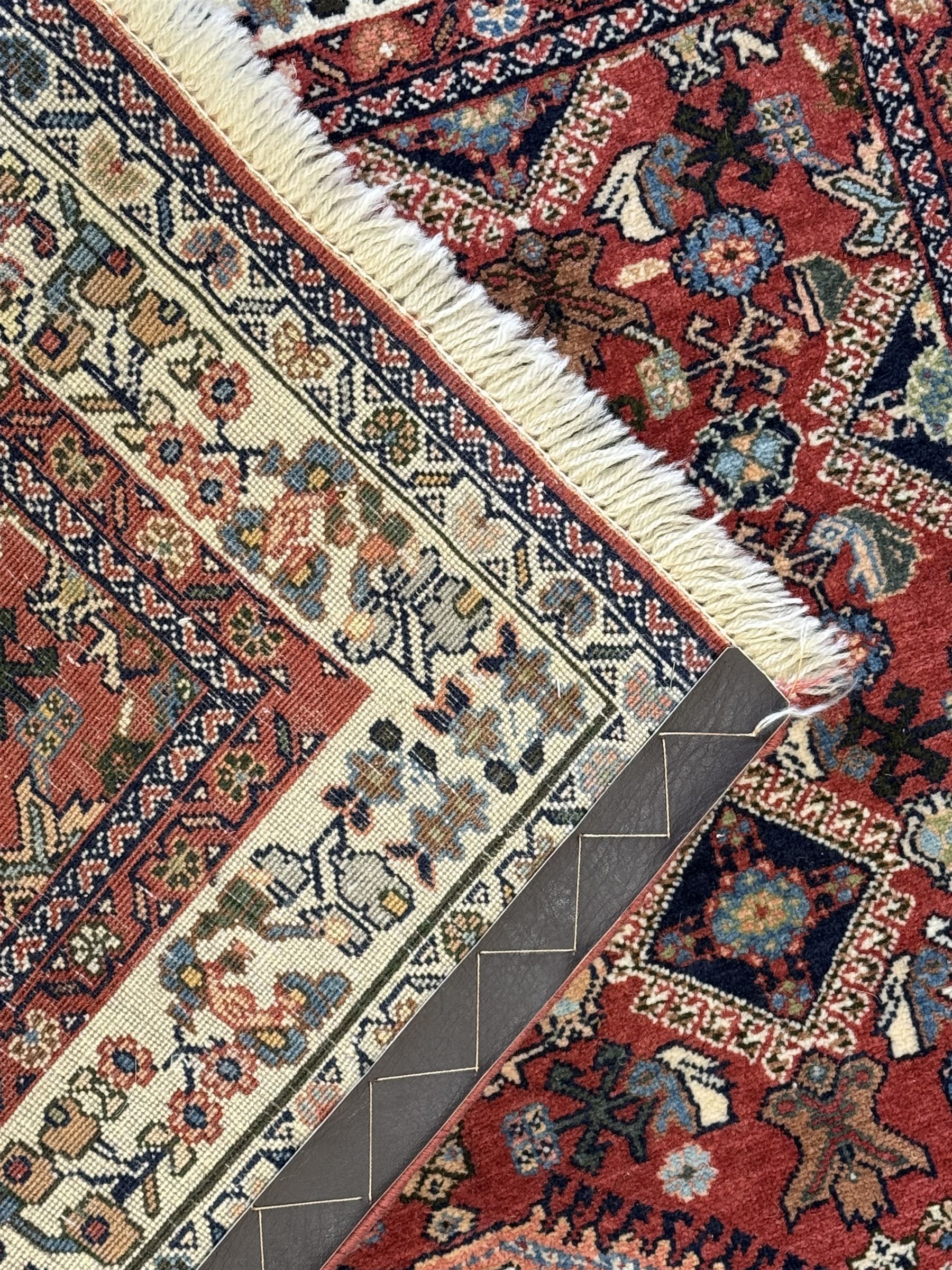 Pair of rugs one Persian hamadan rug central stepped medallion enclosing geometric motifs in ivory and brown, framed by a cream border with scrolling palmettes and fringed ends (H 156cm W 105cm), one Pakistani Bokhara rug rust red ground with repeated Tekke gul motifs within rosette and lozenged borders, fringed ends (H 98cm, W 65cm)