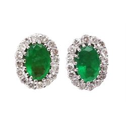 Pair of 18ct white gold oval emerald and round brilliant cut diamond stud earrings, stamped K18