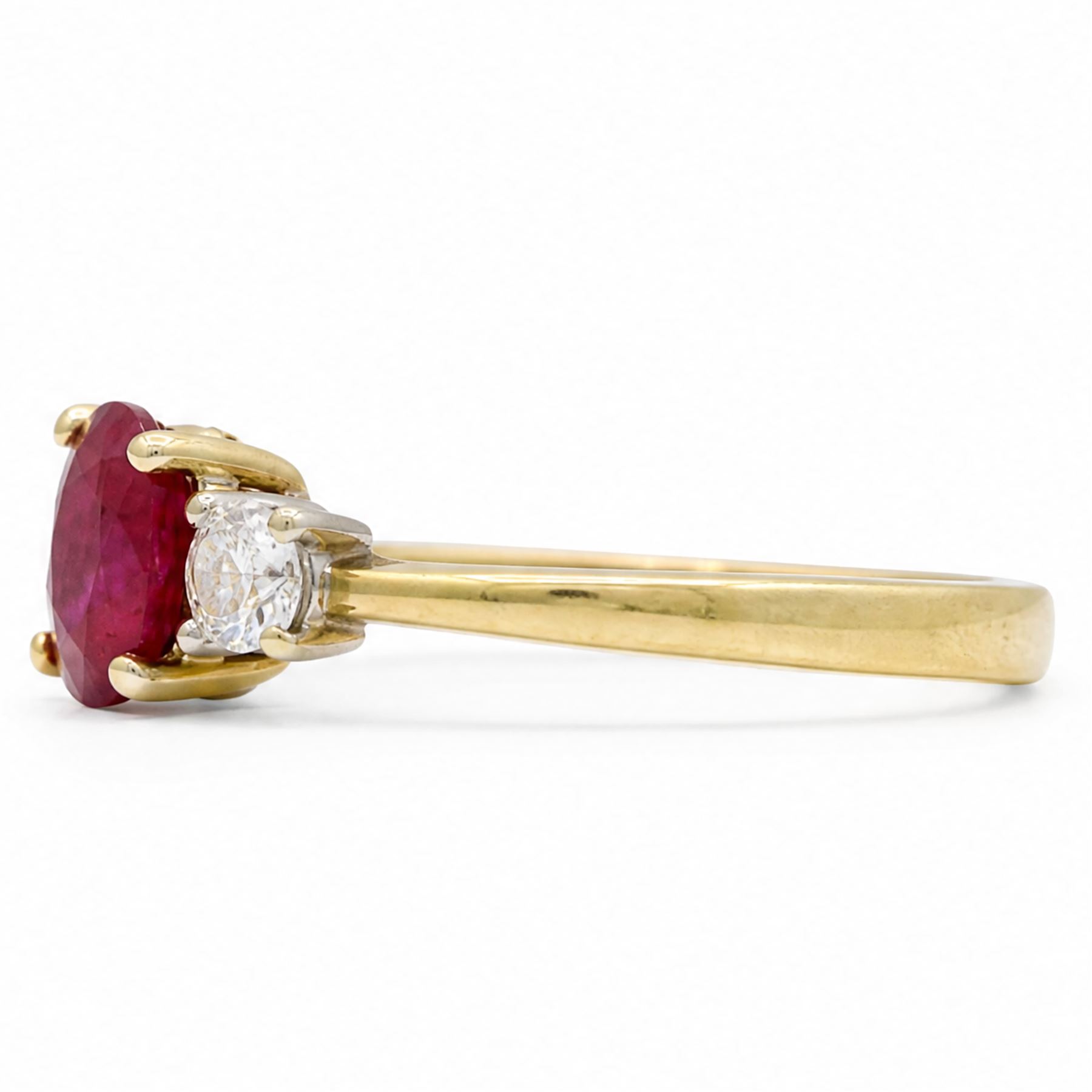 18ct gold ruby and diamond three stone ring, single oval cut ruby of 1.06 carat, with a round brilliant cut diamond set either side, hallmarked, total diamond weight 0.31 carat