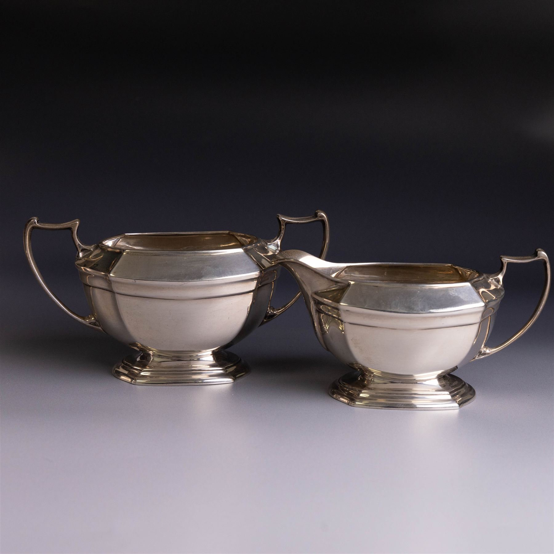 Art Deco three-piece silver tea service, comprising teapot with removable tea strainer, open sucrier and milk jug, all of hexagonal form, the teapot with wooden handle and finial, all hallmarked James Deakin & Sons, Sheffield 1925, together with a matched pair of silver sugar tongs, hallmarked