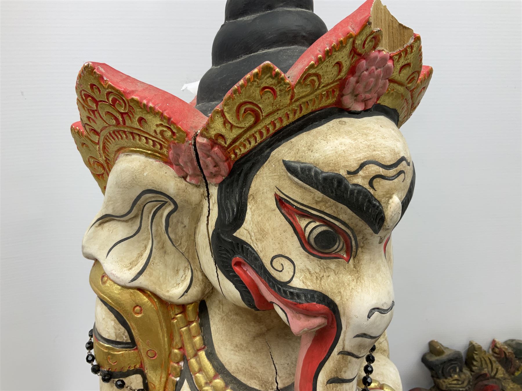 Balinese wood wall panel carved as a dragon boat with passengers, painted in reds and greens with gilding, together with a carved wood figure of Ganesh Deity decorated with gilt, raised upon circular lotus flower plinth, H78cm