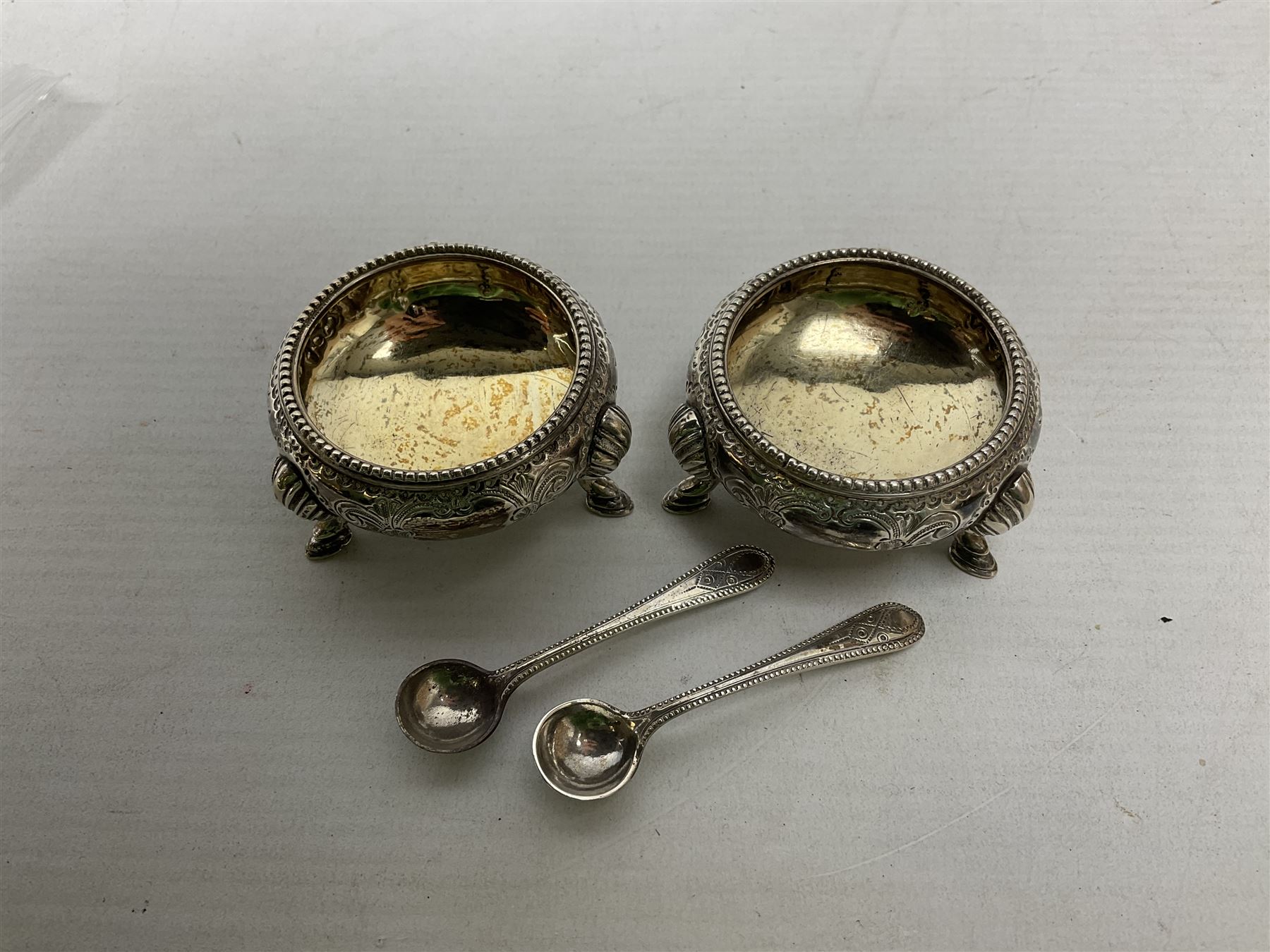 Pair of Victorian silver table salt cellars of cauldron form with gilt interiors, together with accompanying salt spoons, hallmarked Martin, Hall & Co, Sheffield 1879, total weight approx 100.5g