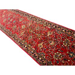 Central Persian Kashan crimson ground runner rug, the field decorated with interlacing branch and stylised flower head motifs, the guarded indigo border with repeating trailing foliate patterns