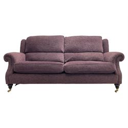 Parker Knoll - pair of large two-seat sofas upholstered in purple fabric, turned mahogany finish front feet with brass cups and castors 