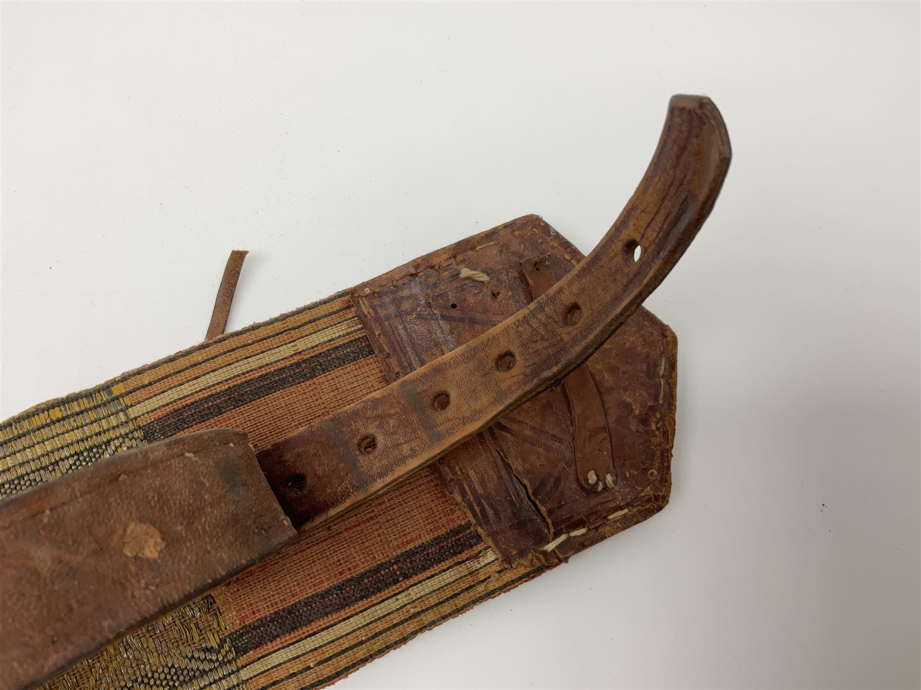 Late 19th century Yemeni Tuza jambiya as worn by religious elite, the 20.5cm curving blade with raised medial ridge, the horn hilt with pique style studwork, in a leather wrapped wooden scabbard with pierced metal mount and leather belt applied with embroidered 'gold' and 'silver' thread work panel; dagger L36cm overall, belt L84cm