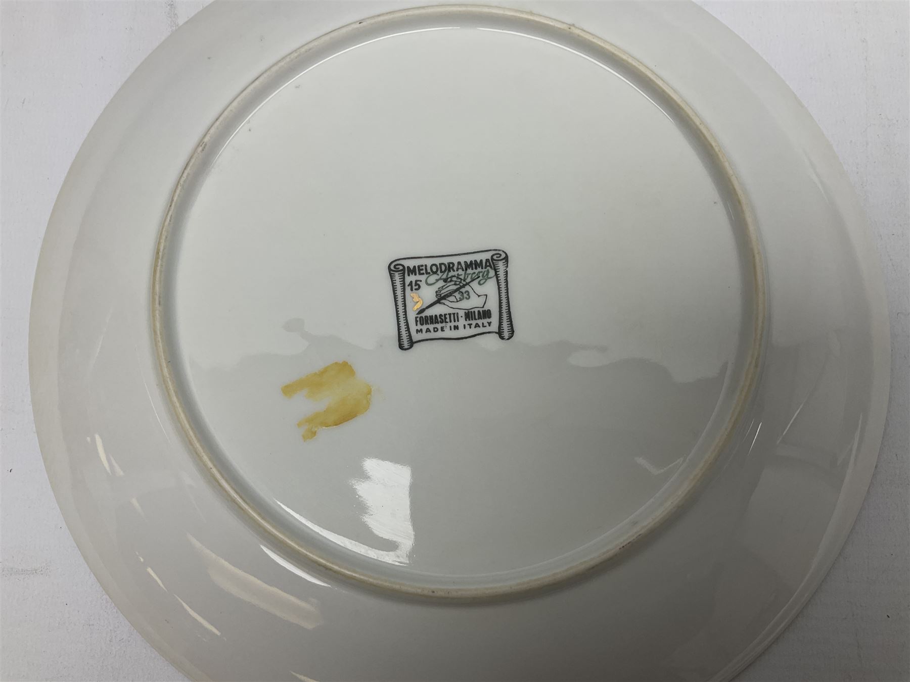 Three Fornasetti plates from the Melodramma series, each depicting a operatic portraits within a border of operatic emblems on gilt ground, with printed mark beneath, D25cm 