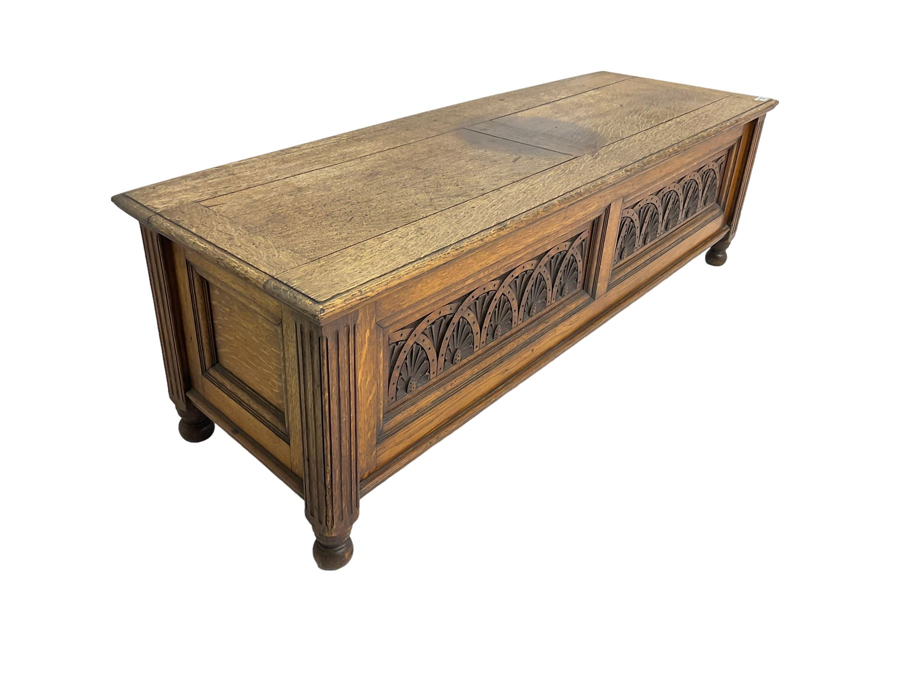 Early 20th century oak ‘bay window’ shaped blanket chest or coffer, hinged top, the front with two lunette carved panels flanked by fluted uprights, on turned feet