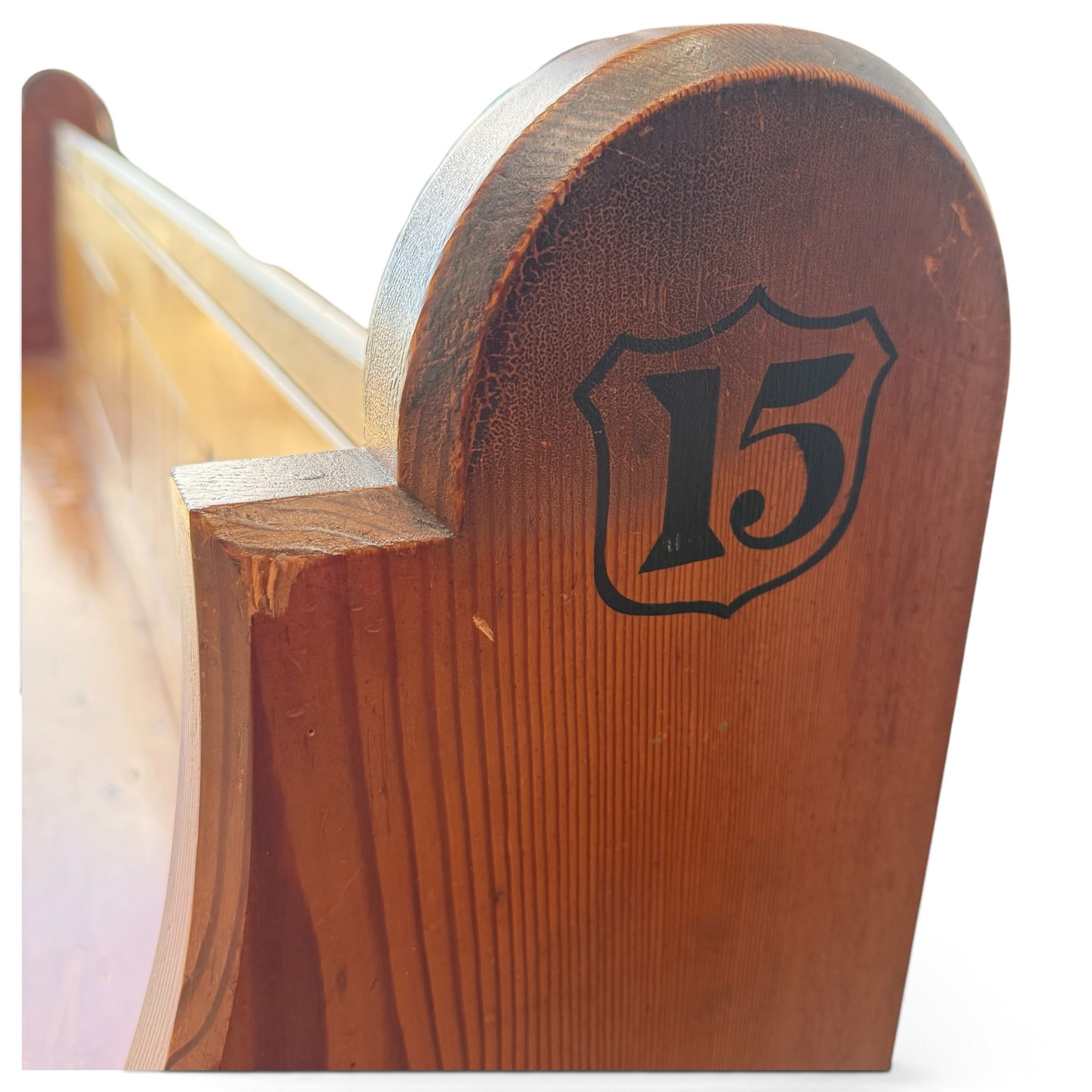 Early 20th century stained pine ecclesiastical church pew, the shaped end supports flanking slatted and panelled back, with black stencilled number '15' to the side