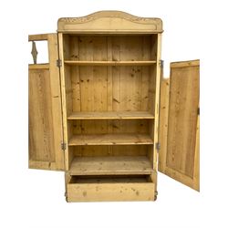 Early 20th century pine double wardrobe, enclosed by panelled and glazed doors, single drawer to base, on turned bun feet