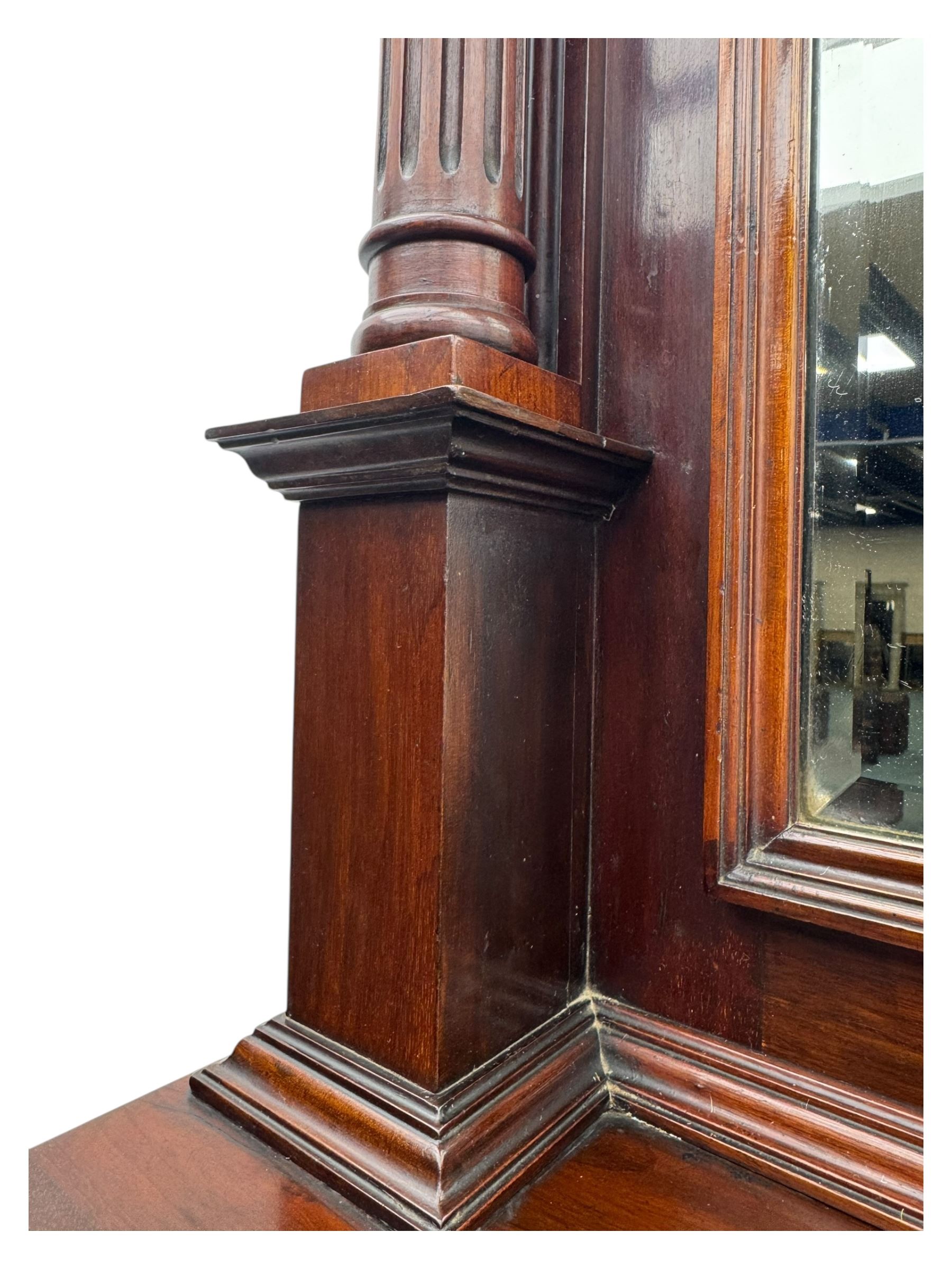 Victorian mirror back press, the arched corniced mirror back flanked by half columns, the base fitted with three drawers and four moulded panel doors with geometric detail, on a block plinth