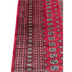 Persian Bokhara red ground carpet, decorated with six rows of traditional Gul motifs, multiple band border decorated with geometric patterns and motifs 