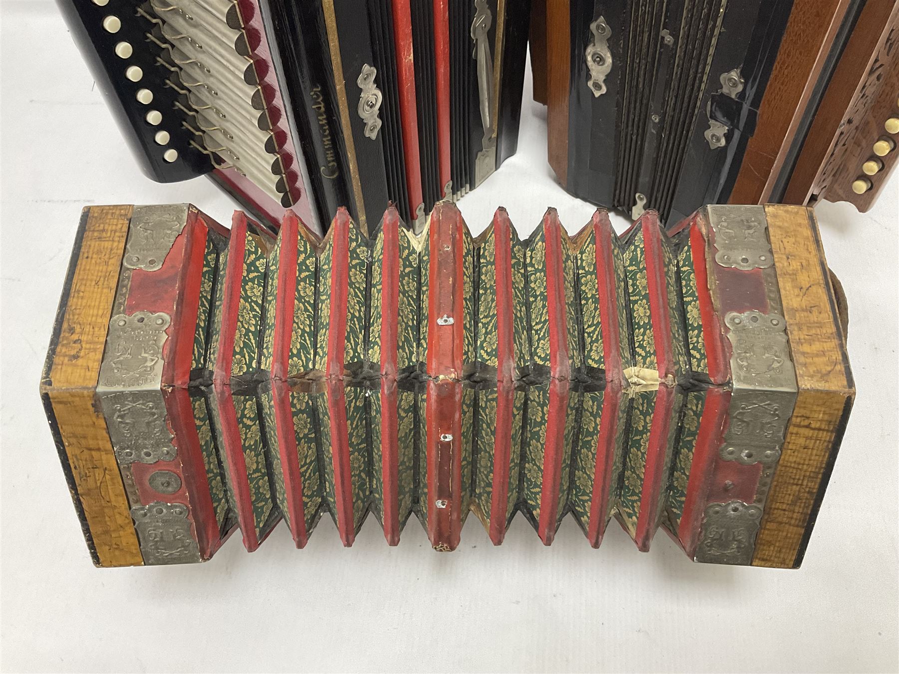Three European concertinas, comprising Viceroy German concertina with 21 keys, hexagon wooden frame and 8 fold bellows
Oak framed concertina with 12 keys and 8 fold bellows
Commander concertina with 12 keys and 12 fold bellows
With tutor