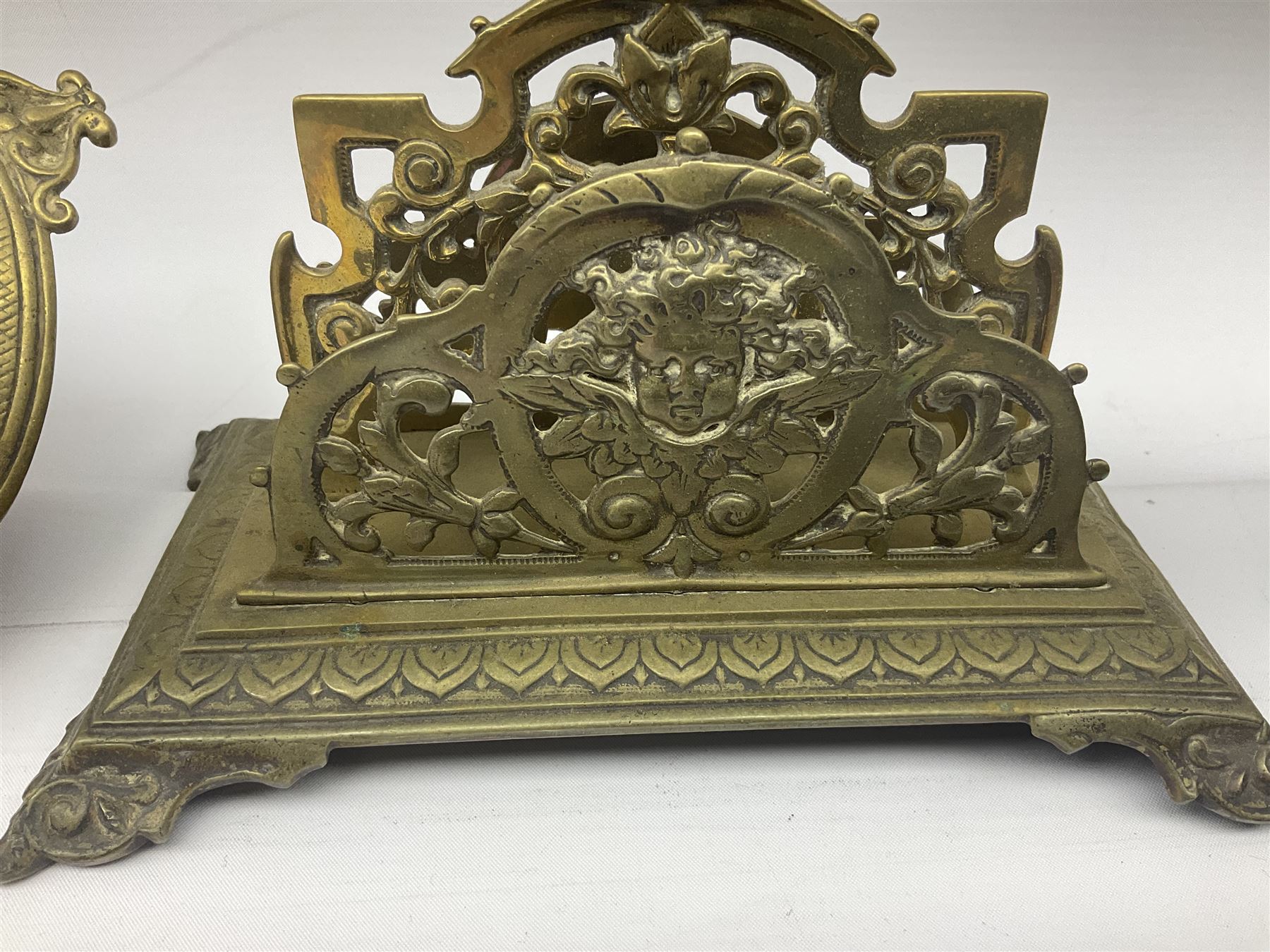 Collection of victorian and later brass desk accessories, to include a letter holder with cherub design, ink well of square form with hinged lid, brass table bell, brass casket with relief decoration, etc  