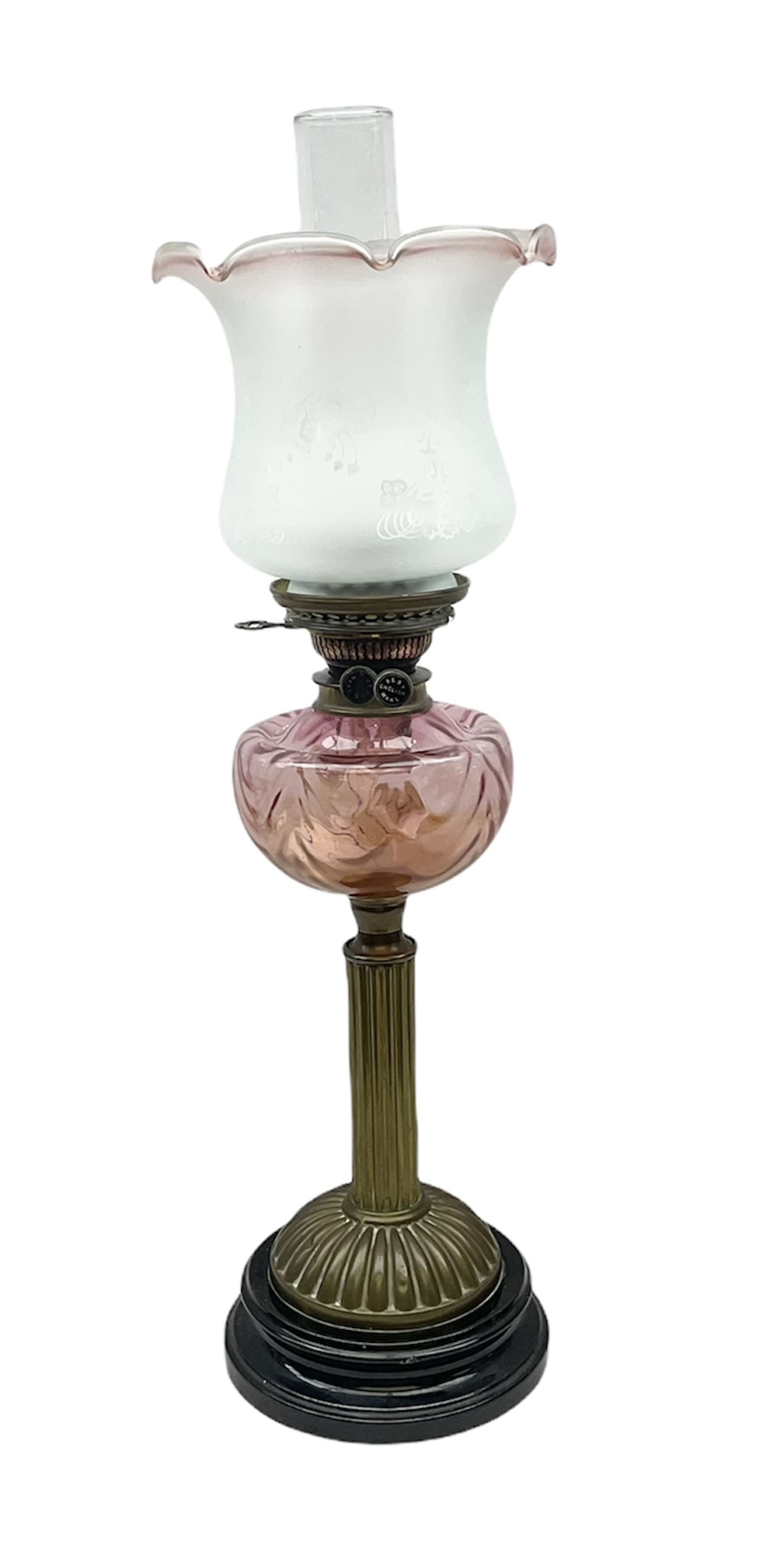 Victorian table oil lamp with black glazed stepped circular base, reeded brass column, moulded pink glass reservoir, duplex burner and frilled rim frosted glass shade with clear glass chimney H69cm