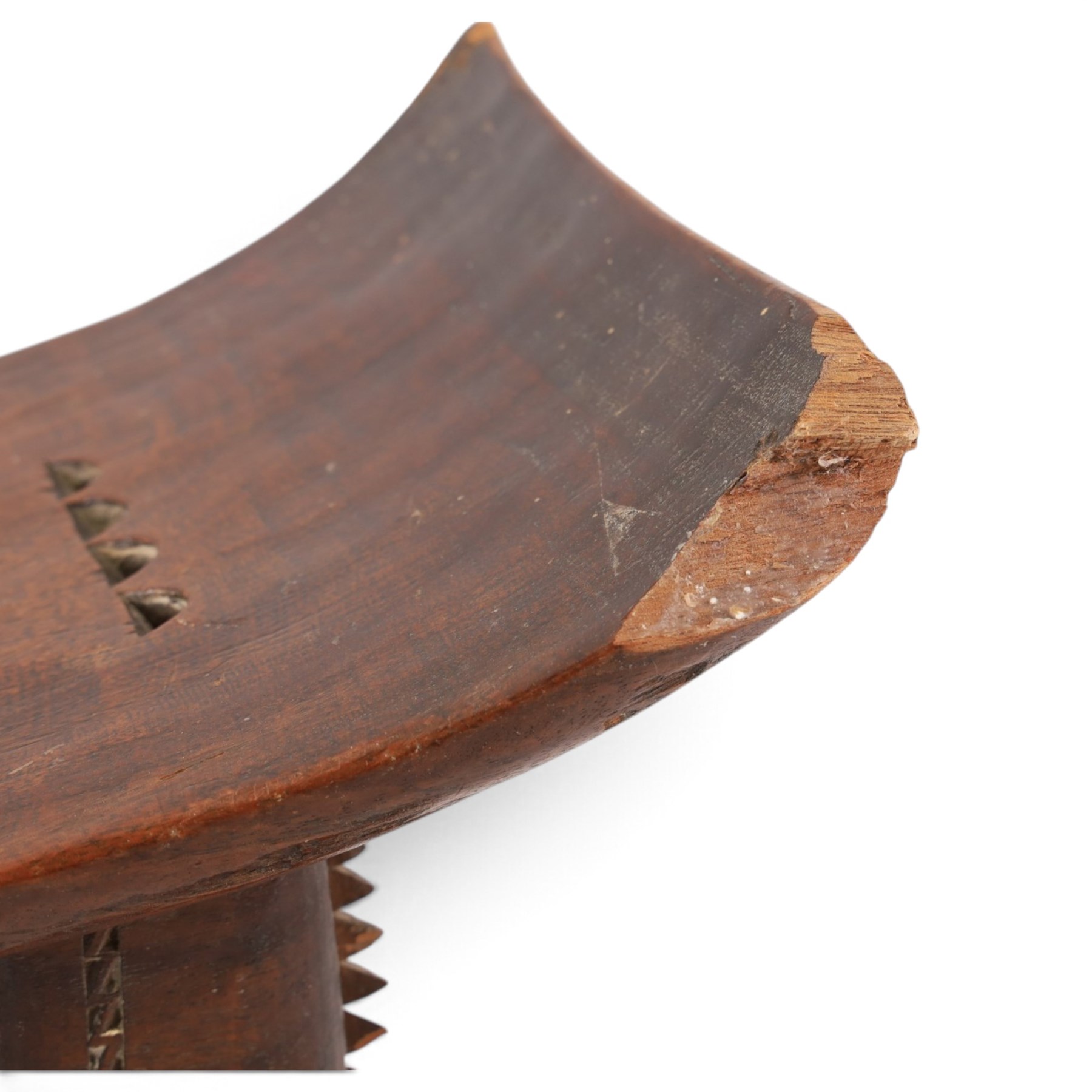 African carved hardwood headrest, having flared edges, raised on a stepped plinth base with further carved detailing, H34cm