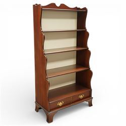 Early 20th century mahogany waterfall bookcase, shaped and serpentine side uprights with scalloped cresting, fitted with four open shelves above two short drawers with brass drop handles, raised on shaped bracket feet