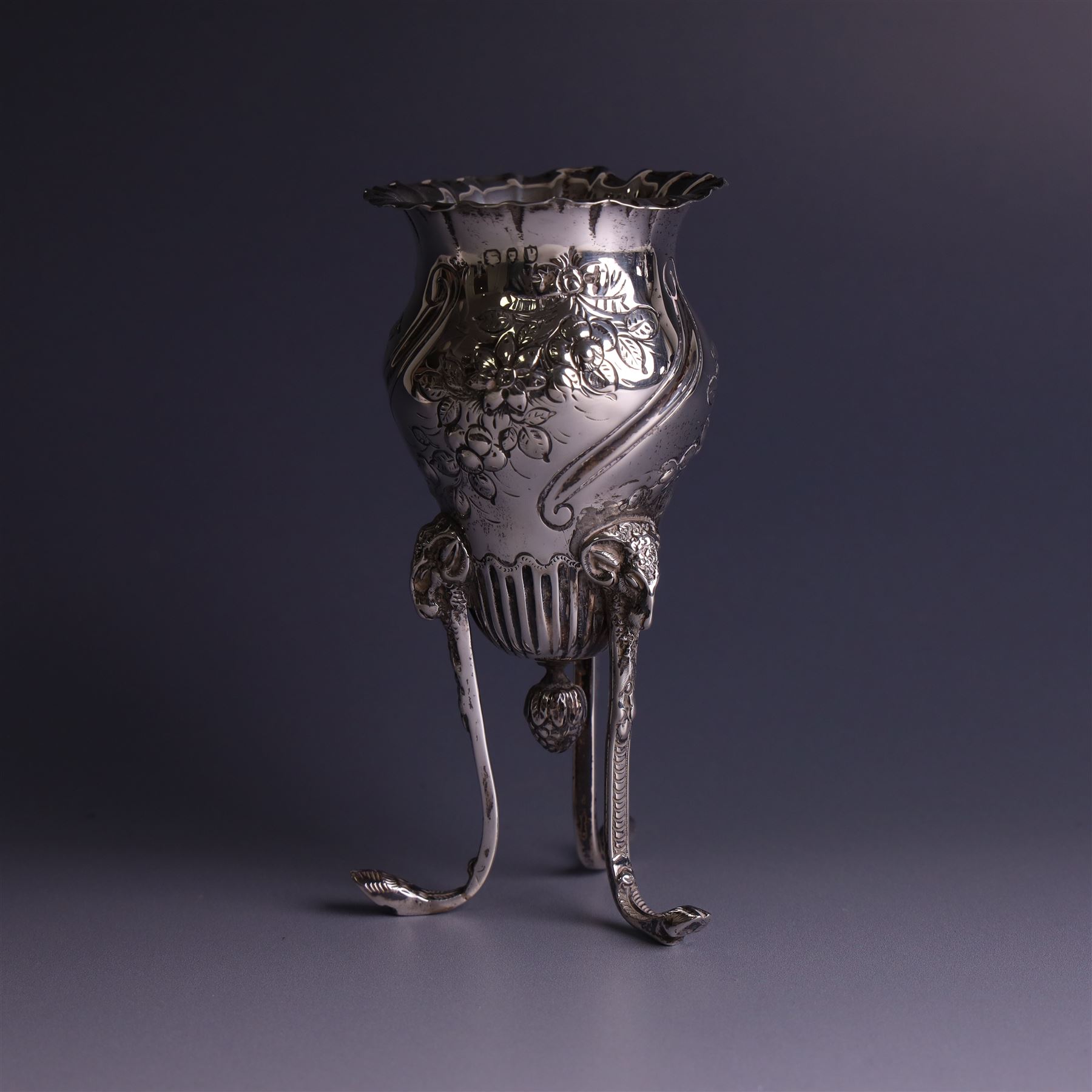 Late Victorian silver vase, of baluster form with fluted rim, the body with embossed floral decoration, upon three tall legs with ramshead mounts, hallmarked William Comyns & Sons, London 1890, H13.5cm