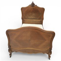 Early 20th century French walnut single bedstead, the shaped and moulded headboard with carved foliate crest above a panelled field, with conforming serpentine footboard with moulded reserves, the shaped apron with applied carved detail, raised upon cabriole supports with carved knees