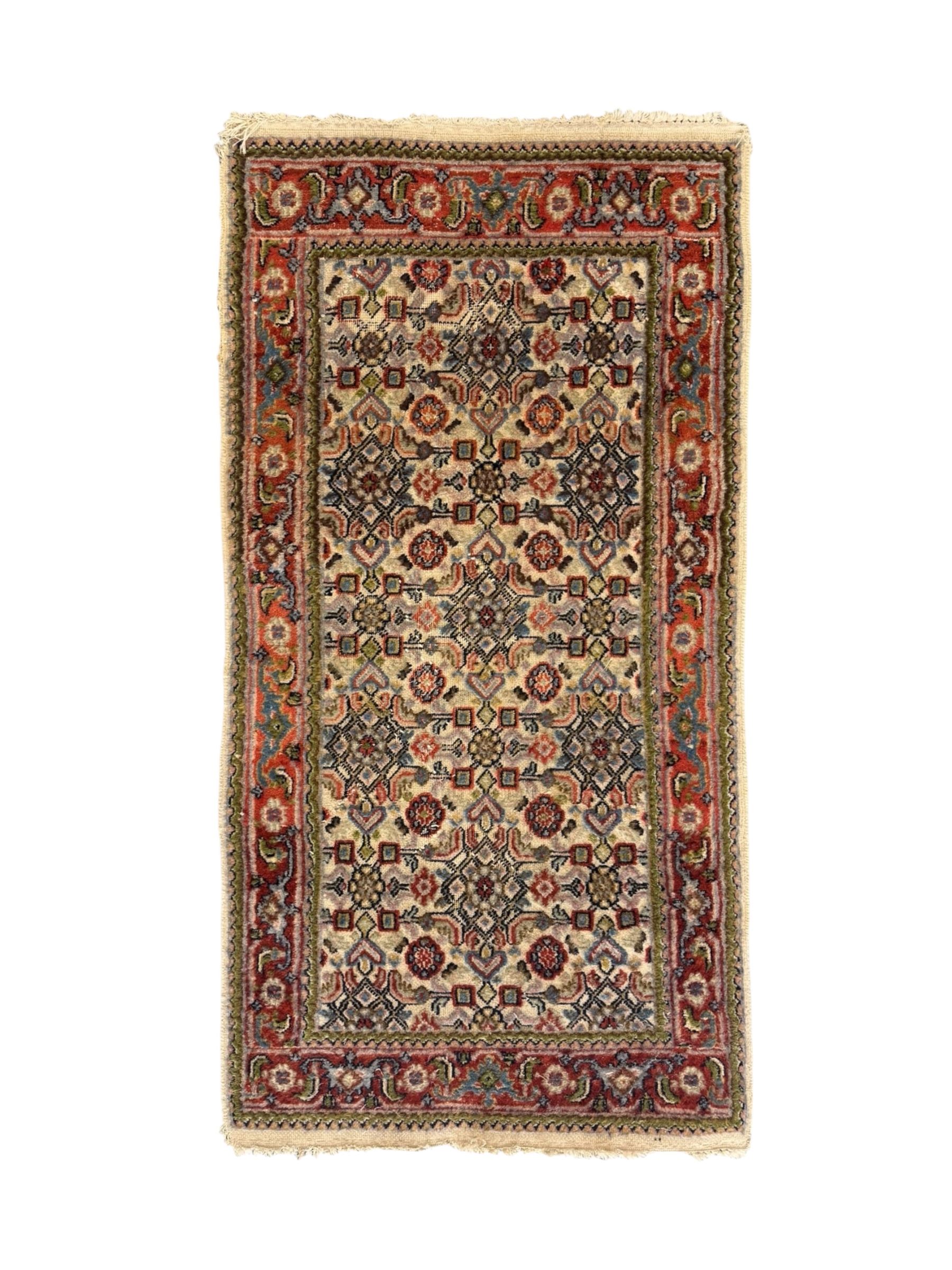 Persian-style wool rug, cream field with floral and geometric motifs, wide floral border (74cm x 142cm); Persian wool rug, beige field with dense floral patterns, narrow floral border (70cm x 144cm); Tribal wool rug, red and navy with diamond motifs (96cm x 60cm); Persian pictorial wool rug, black field with vase, birds, and floral border (70cm x 73cm)